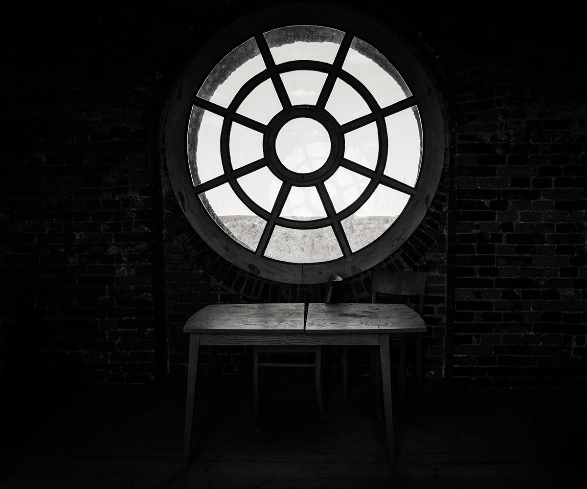 sw-Foto: rundes Kirchenfenster mit Tisch davor